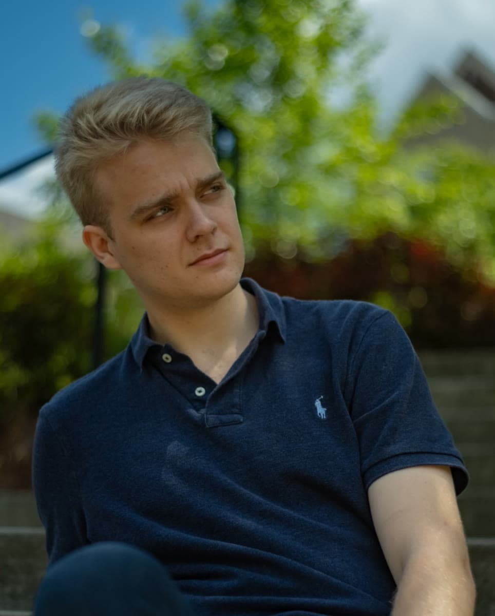 Andrew Bredeson seated outdoors in a blue polo shirt