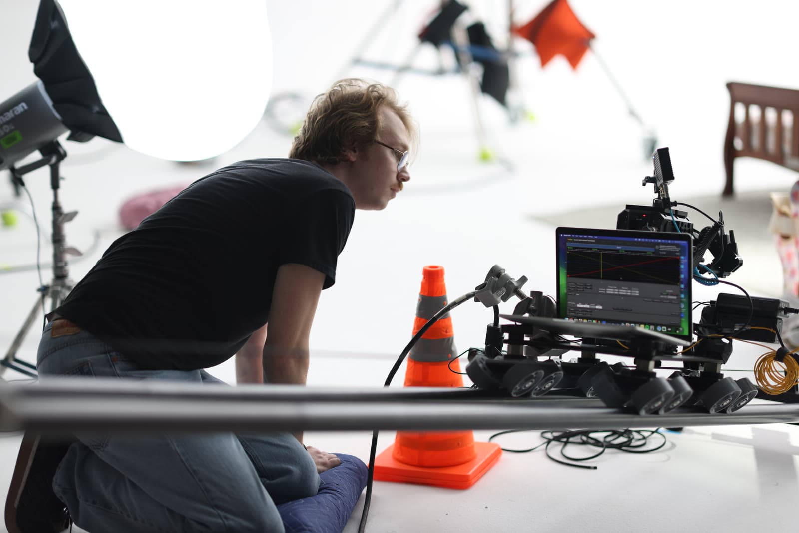A crew member crouches beside a camera rig on a white studio floor