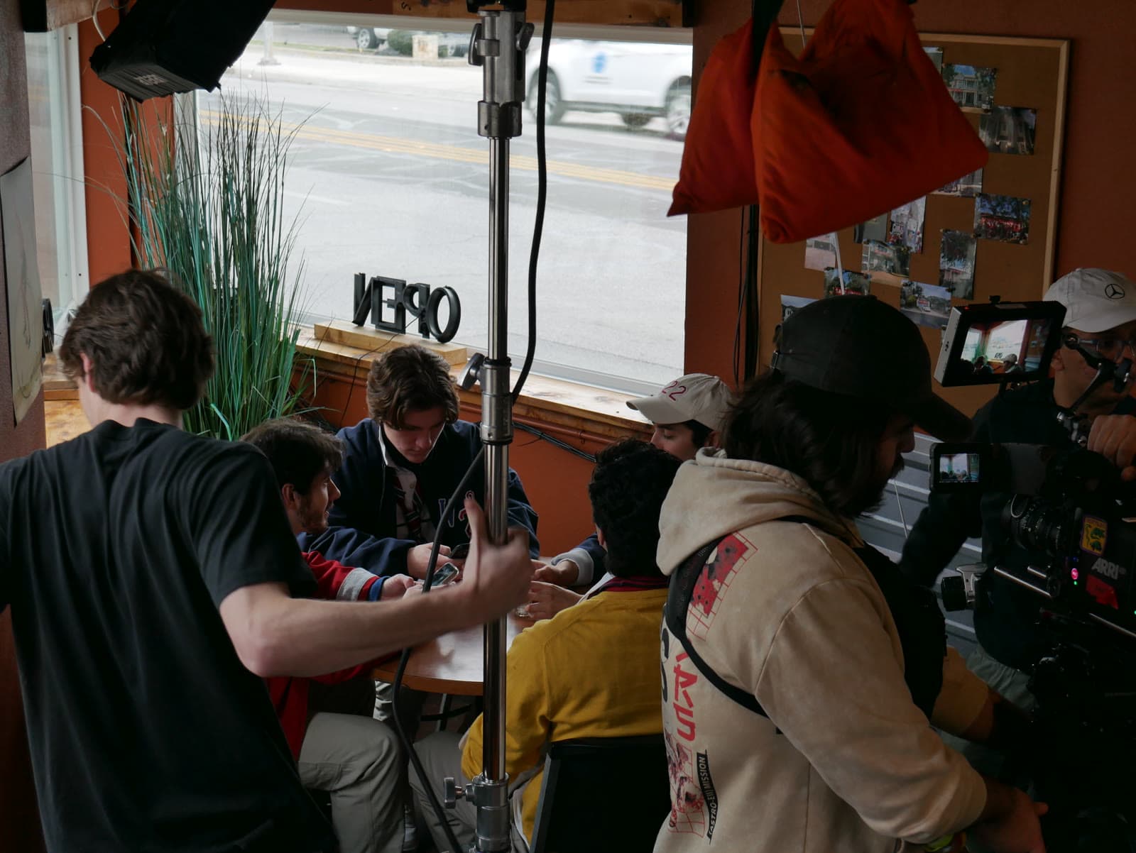 The crew films a scene in a diner booth by the window