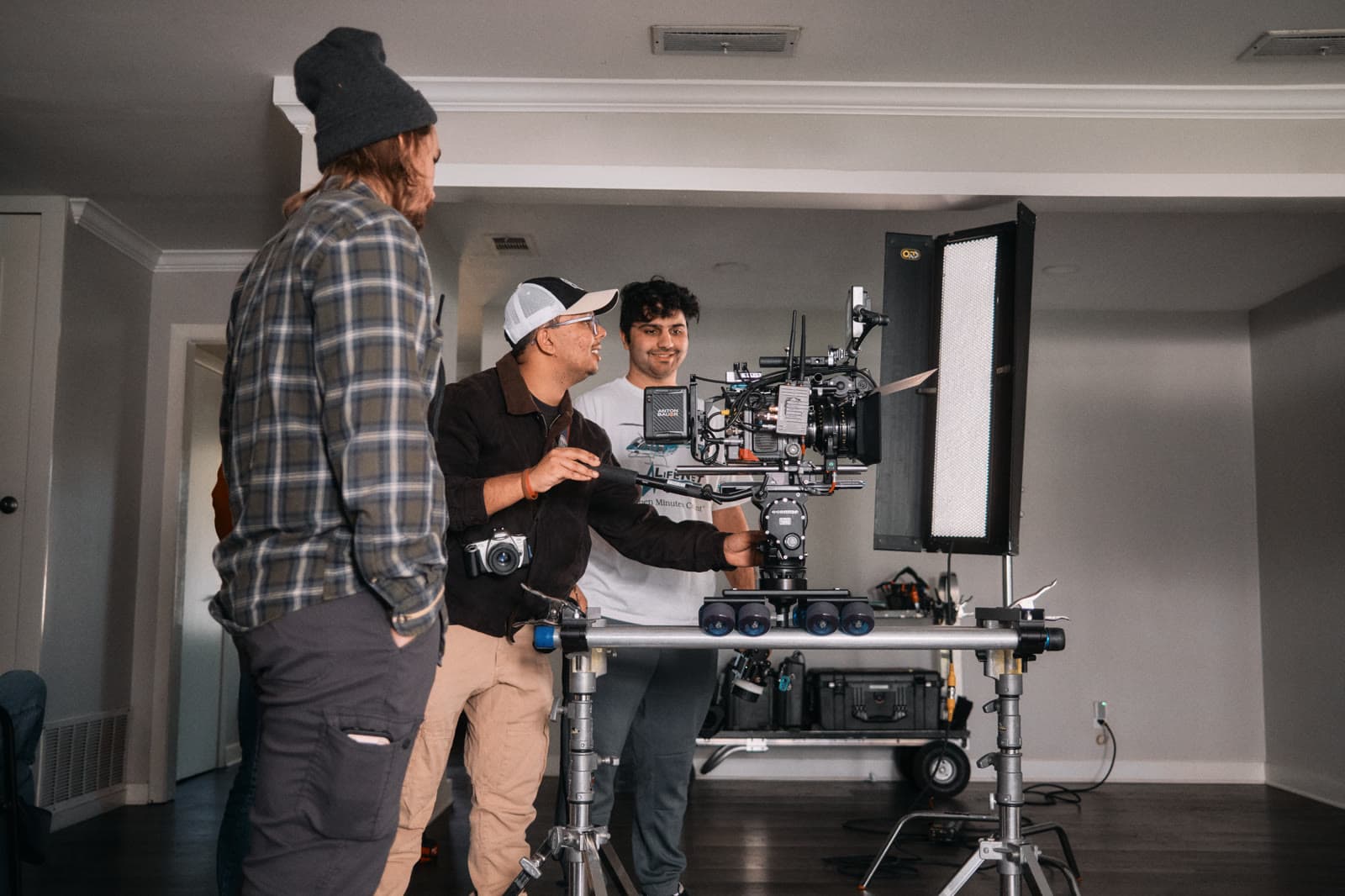 Three crew members gather around a camera cart on location