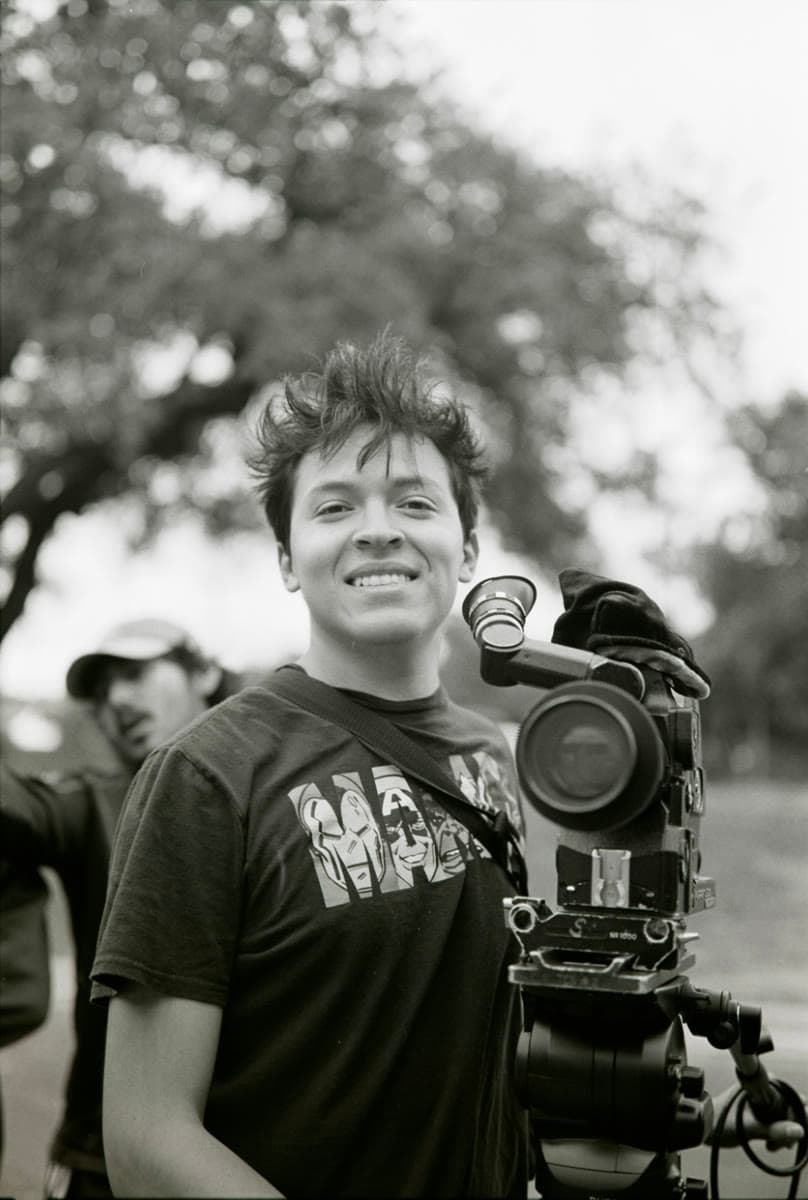 Marlon Rubio Smith smiling and holding a film camera, in black and white
